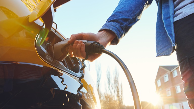 A person attaching EV charger to an electric vehicle