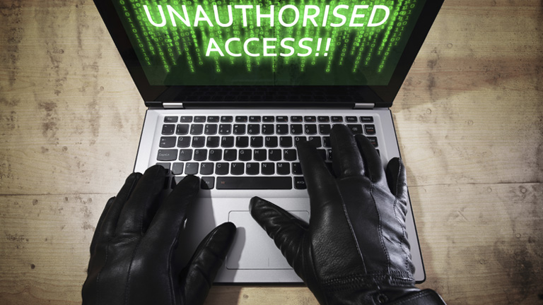 Hacker trying to do a cyber attack via laptop with Unauthroised Access showing on the screen