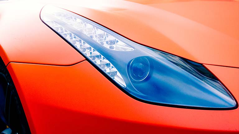 The passenger side headlight on a red car